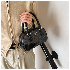 Detail of a mini bowling bag featuring mixed black leather and grey tweed fabric textures
