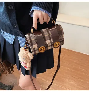 Dettaglio della borsa vintage a quadri con serrature dorate e ciondolo orsetto di peluche