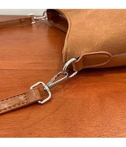 Close-up of silver metal hook on a brown suede and leather crossbody bag