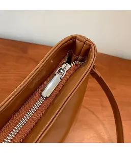Close-up of high-quality smooth silver metal zipper on a brown leather shoulder bag