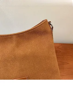 Macro shot of brown suede texture and metal D-ring buckle on stylish shoulder bag