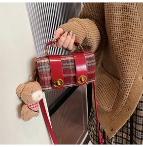 Dettaglio della borsa a tracolla in pelle rossa e plaid con chiusure oro e orsetto