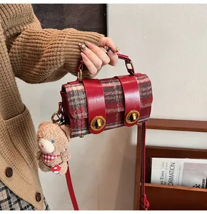 Dettaglio borsa in tweed a quadri rossi con cinturini in pelle e fibbie dorate