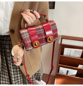 Dettaglio borsa a mano scozzese rossa con finiture lucide e ciondolo a forma di orso