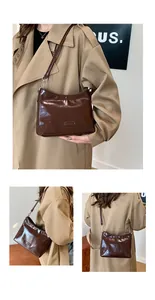 Detail of dark brown glossy patent leather shoulder bag with a metal logo plaque