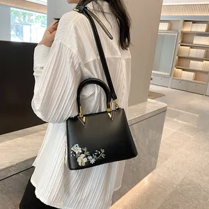 Black leather tote bag with floral embroidery and gold hardware for women's daily commute