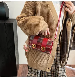 Dettaglio della borsa a tracolla scozzese rossa con chiusura a rotazione e charm a orsetto
