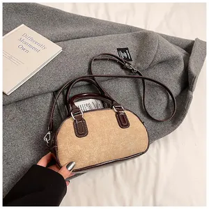 Detail view of canvas and brown leather bowling bag placed on a grey woolen coat
