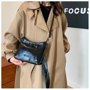 Chic glossy black square crossbody bag shown on model wearing khaki trench coat