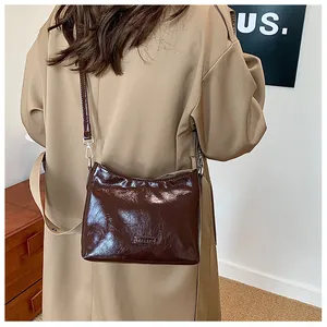 Close-up of deep brown glossy patent leather shoulder bag with a metallic buckle detail