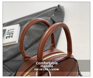Detail of comfortable round handles on brown leather bag with golden metal hardware