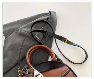Detail view of adjustable leather strap and gold hardware on brown crossbody bag