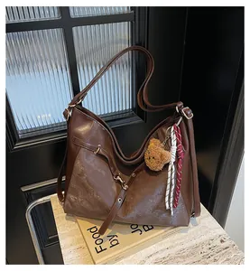 Detail of vintage brown tote bag with bear charm on marble surface background