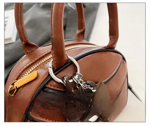 Close-up of caramel leather baseball bag with gold zipper and chocolate charm detail