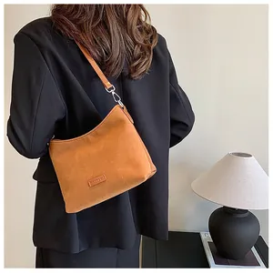 Detail of tan suede shoulder bag showing matte texture and silver metal hardware