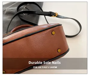 Close-up of brown textured leather bag base with protective golden metal studs