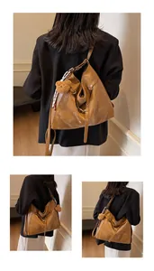 Detail of a brown leather hobo bag with a plush bear charm and decorative silk scarf