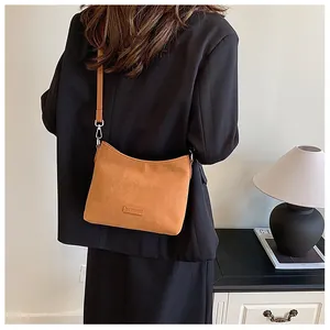 Detail of camel brown matte leather shoulder bag featuring vintage square logo and silver metal hooks