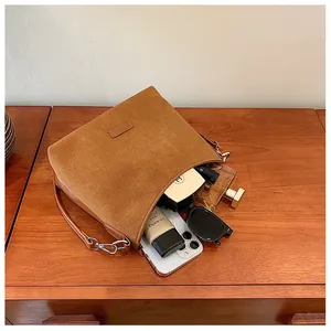 Brown suede shoulder bag interior showing capacity for phone, sunglasses and cosmetics