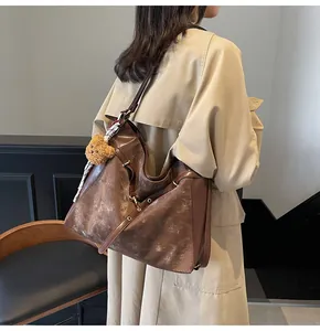 Detail of vintage large tote bag with bear charm and silk scarf on beige coat