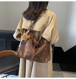 Detail of vintage brown tote bag with bear charm and scarf shown on model