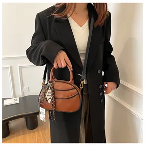 Detail of a brown leather baseball bag with textured finish and chocolate charm