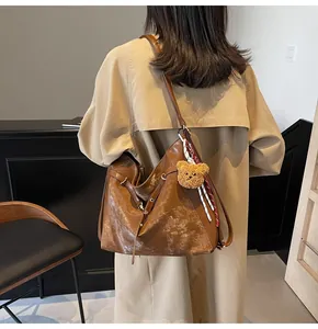 Detail of vintage brown tote bag with bear charm and ribbon on model's shoulder