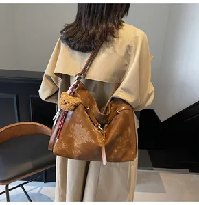 Detail of vintage brown tote bag with marble texture and plush bear charm on a model