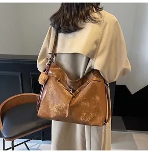Close-up of vintage brown tote bag with plush charm and decorative floral silk scarf