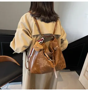 Detail view of a vintage brown tote bag with bear charm and scarf on a model