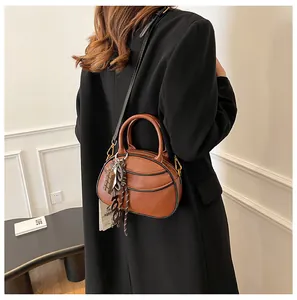 Brown oval crossbody bag with chocolate charm shown on model from a side-back angle