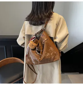Detail of vintage brown tote bag with plush bear charm and decorative silk scarf accessory