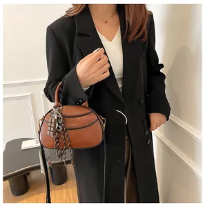 Detailed shot of a vintage brown leather curved bag with chocolate-shaped charm and strap