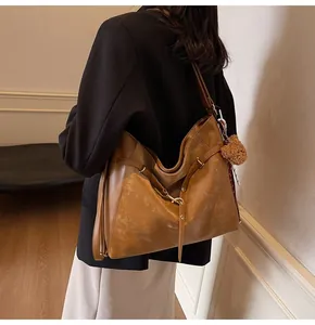 Brown vintage tote bag with adjustable strap and bear pendant shown on model's shoulder