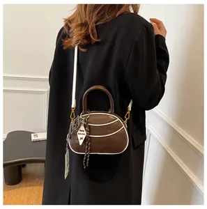 Detail of dark brown handbag with white contrast piping and decorative geometric tag