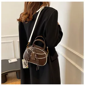 Detail of a chic dark brown baseball bag with white trim and stylish charm pendants