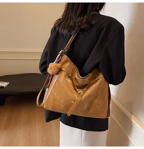 Close-up of vintage brown leather tote bag with plush bear charm and striped strap detail