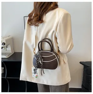 Brown oval crossbody bag with contrast piping and adjustable shoulder strap on model