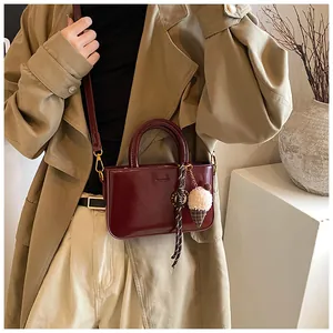Détail du sac à main rouge foncé avec pendentif en peluche et poignée élégante pour femme