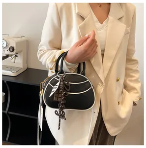 Detail showing matte black bowling bag with white contrast piping and cute charms