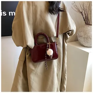 Détail d'un sac à main en cuir verni bordeaux avec charm pendentif glace en peluche