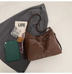 Detail of vintage brown tote bag with metal clasp and plush bear charm on a grey suit