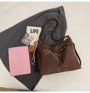Detail of a dark brown Hobo bag with cross straps and a cute teddy bear charm on fabric