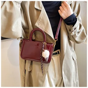 Détail du sac à main en cuir verni bordeaux avec pendentif glace et bandoulière