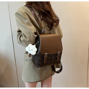 Détail d'un sac à dos vintage marron imprimé avec breloque nuage et boucles métalliques