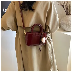 Détail d'un sac à main rouge brillant avec un charmant pendentif en peluche sur fond manteau