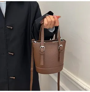 Close-up of brown litchi pattern leather bucket bag with metallic buckle detail