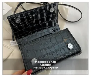 Détail du sac en cuir noir gaufré crocodile avec fermeture à bouton pression magnétique