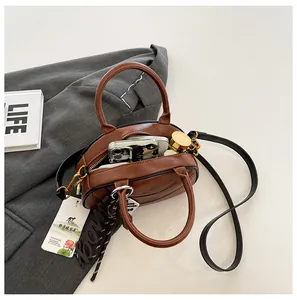 Brown leather baseball bag detail showing internal storage capacity for phone and lipstick