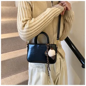 Détail du sac à main noir verni avec bandoulière réglable et breloque peluche glace